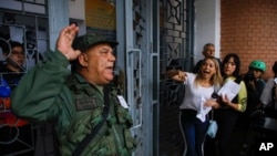 Un oficial de la Guardia Nacional se dirige a los votantes que hacen fila en la Escuela Andrés Bello. (AP Foto/Cristian Hernández)