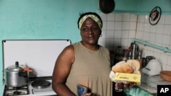 María de los Ángeles Pozo, trabajadora retirada de una escuela, posa para una foto en su cocina con algunos de los alimentos subvencionados que recibió por con la libreta de abastecimiento estatal en La Habana.