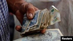 Un hombre sostiene un fajo de pesos cubanos. En Cuba circulan tre smonedas con cuatro tipos de cambio. (REUTERS/Desmond Boylan/Archivo)