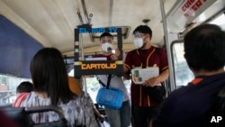 Los periodistas Juan Pablo Lares, a la derecha, y Maximiliano Bruzual, en la pantalla de cartón, en un noticiero alternativo en un autobus que surgió por las presiones del gobierno de Venezuela contra la prensa independiente. (AP Photo/Ariana Cubillos).