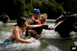 El migrante venezolano Álvaro Calderini lleva a su sobrina a través de un río cerca de Bajo Chiquito, Panamá, después de cruzar caminando el Tapón del Darién. (AP/Matías Delacroix, Archivo)