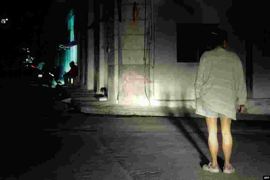 Una mujer está parada en una calle iluminada por las luces de un automóvil durante un apagón nacional&nbsp; el 4 de diciembre de 2024.