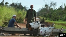 Hombres miran cables eléctricos caídos después del paso del huracán Rafael en Guira de Melena, provincia de Artemisa, el 7 de noviembre de 2024