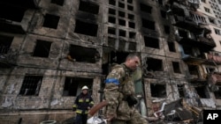 Soldados y bomberos ucranianos buscan en un edificio derruido tras un ataque en Kiev, Ucrania, el lunes 14 de marzo de 2022. (AP Foto/Vadim Ghirda)